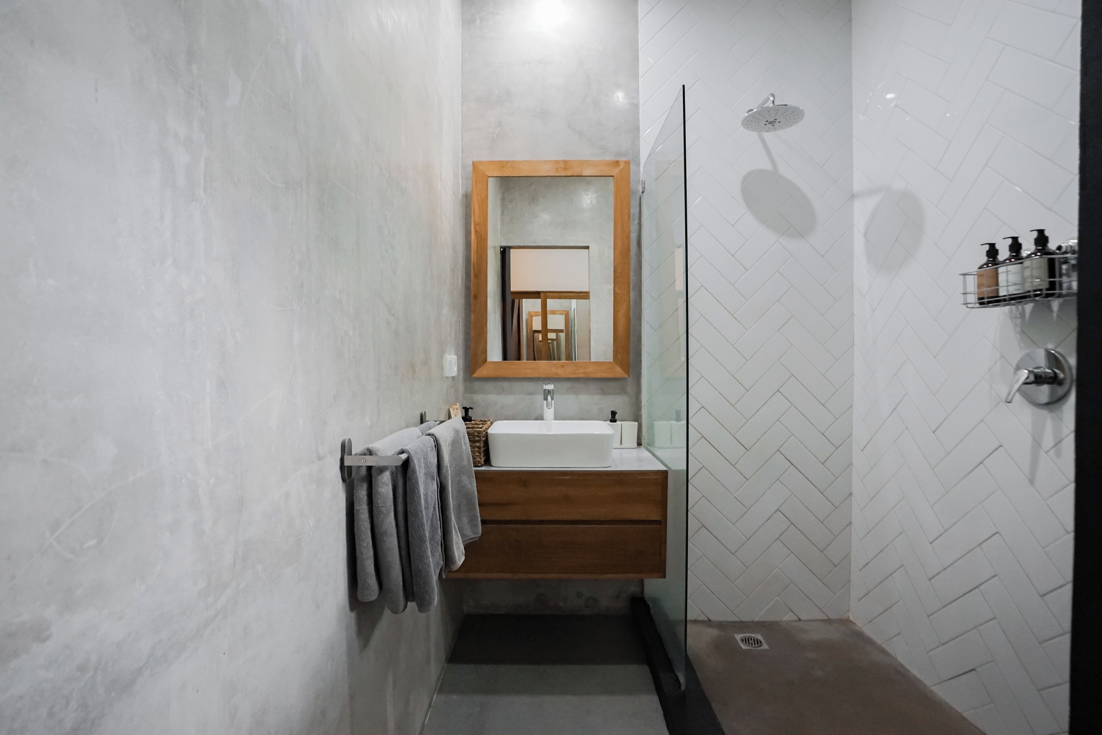 Un baño moderno con tocador de madera, un espejo y ducha.