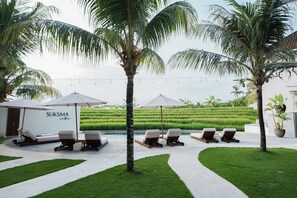 A resort with a swimming pool, lounge chairs, and palm trees. - Suksma Guesthouse (Tumbak Bayuh)