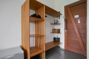 A modern kitchen with wooden shelves, a kettle, and a basket. - Suksma Guesthouse (Tumbak Bayuh)