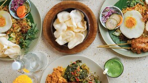 Taula amb diferents plats, com ara arròs, verdures i carn, a més de condiments i begudes.