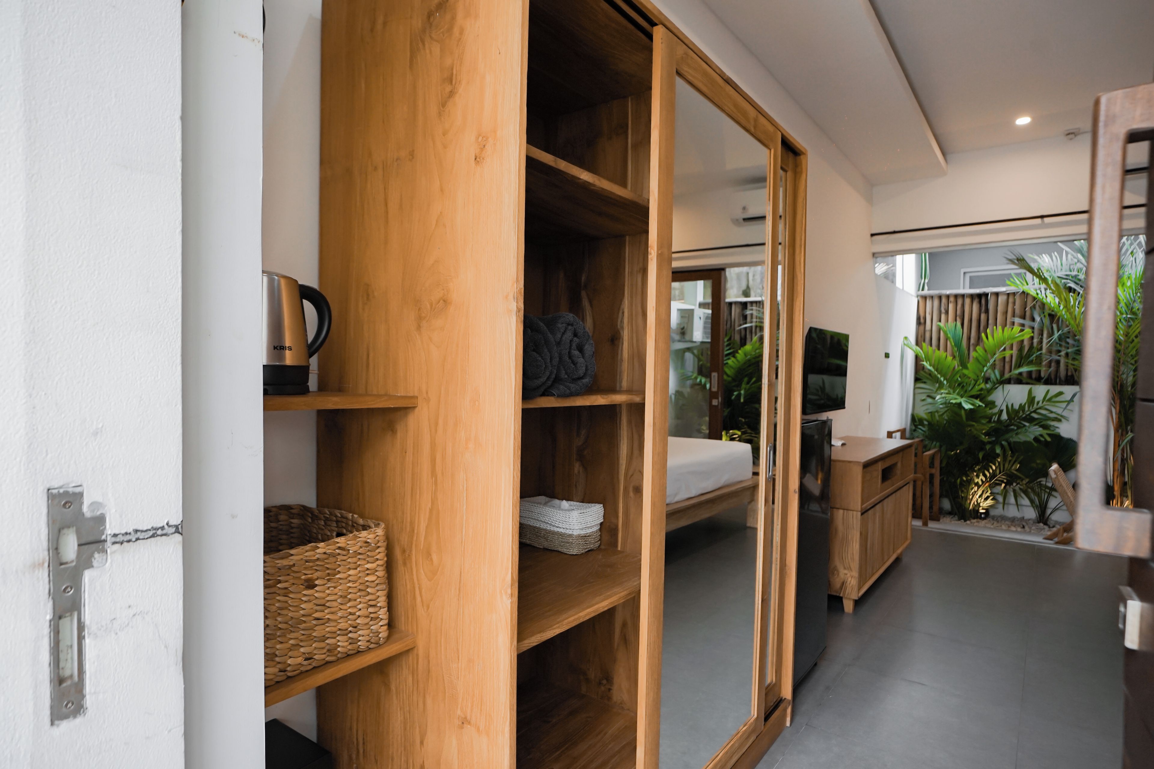 Une chambre moderne avec une armoire en bois, un lit, une télévision et un petit coin cuisine.
