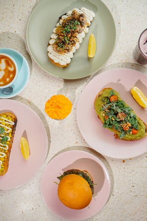 Una mesa con varios platos, incluyendo un sándwich, un tazón de sopa y un postre.