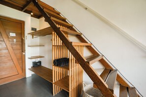 A wooden staircase with built-in shelves and a small radio. - Suksma Guesthouse (Tumbak Bayuh)