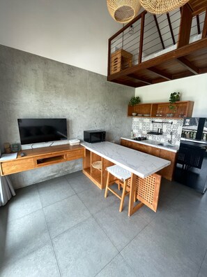 Una cucina moderna con una grande TV, mobili in legno e un'area pranzo.