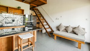 A modern kitchen with a wooden counter, a built-in stove, and a hanging light fixture. - Suksma Guesthouse (Tumbak Bayuh)