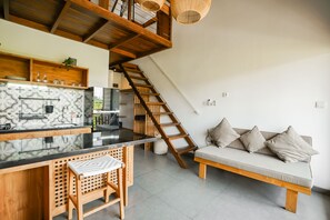 A modern kitchen with a wooden counter, a built-in stove, and a hanging light fixture. - Suksma Guesthouse (Tumbak Bayuh)