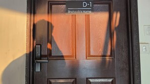 Tumma puuovi, jonka yläpuolella on kyltti, jossa lukee: ”D-1, Shahzaibin koti”.