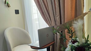 A room with a white chair, an HP laptop on a stand, a decorative plant, and a curtain.