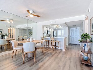 Eine moderne Küche mit einer zentralen Kochinsel, Holzboden und einem Essbereich mit rundem Tisch und Stühlen.