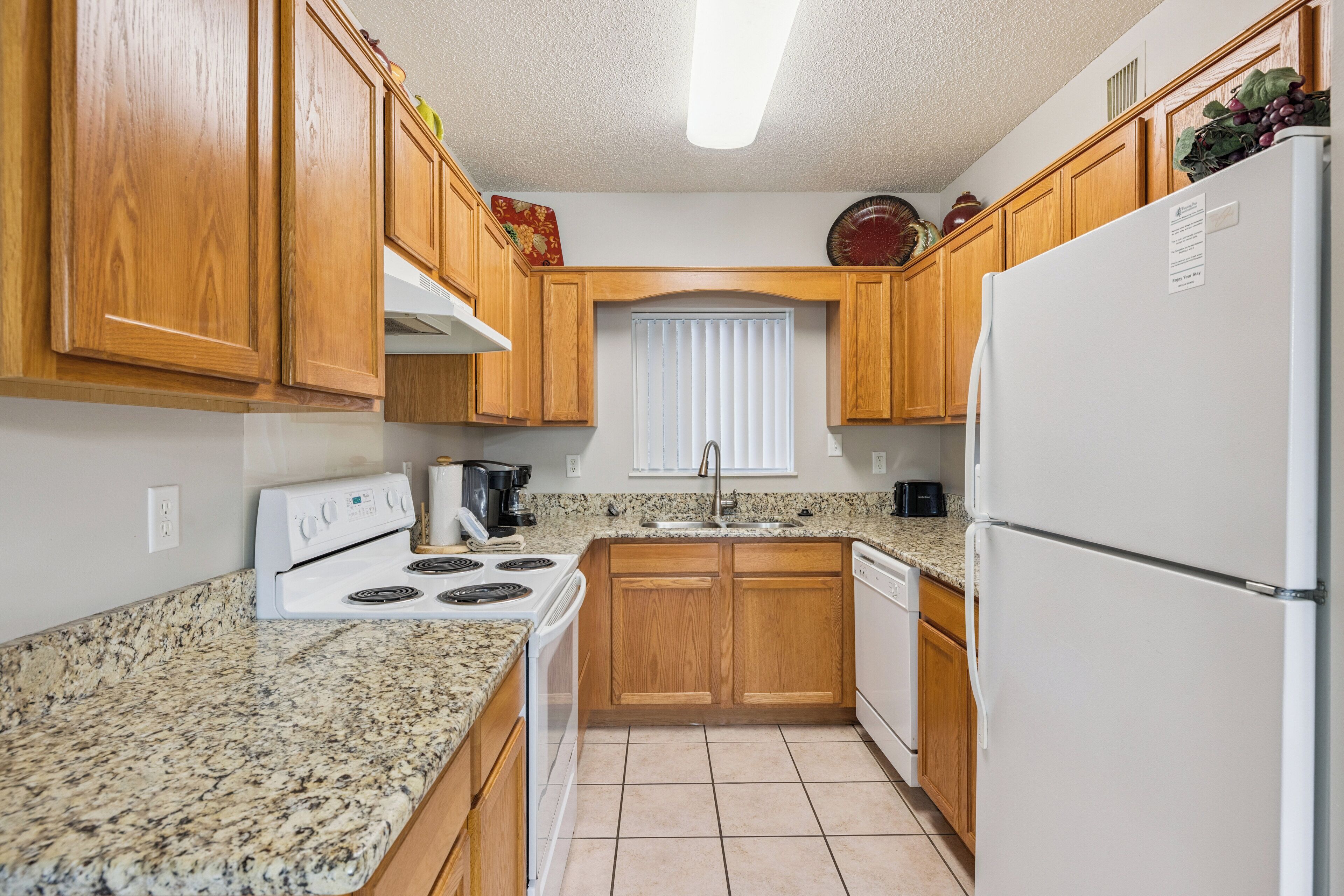 Una cocina con armarios de madera, estufa blanca, un lavabo y un refrigerador.