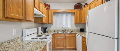 Una cocina con armarios de madera, estufa blanca, un lavabo y un refrigerador.