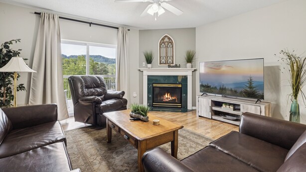 A living room with a fireplace, leather sofas, a television, and a ceiling fan. - 3 King BD |3 BA| Indoor Pool| Walk-In Level | Free Dollywood Tkt & More! (Pigeon Forge)