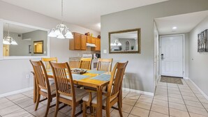 A dining area with a wooden table and chairs, a chandelier, and a kitchen in the background. - 3 King BD |3 BA| Indoor Pool| Walk-In Level | Free Dollywood Tkt & More! (Pigeon Forge)