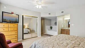 A bedroom with a bed, a TV, a dresser, a chair, and a bathroom with a bathtub and sink. - 3 King BD |3 BA| Indoor Pool| Walk-In Level | Free Dollywood Tkt & More! (Pigeon Forge)