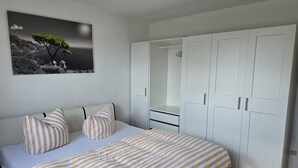 A bedroom with a bed, striped bedding, a nightstand, a wardrobe, and a framed picture on the wall. - Apartment on the mountain Schloßberg with beautiful view Pet friendly (Heideck)