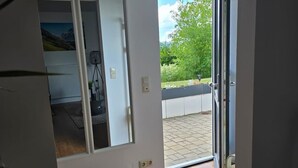 A room with a sliding glass door leading to a balcony with a view of greenery and a clear sky. - Apartment on the mountain Schloßberg with beautiful view Pet friendly (Heideck)