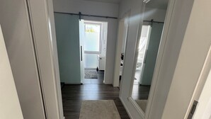 Een gang met vloerkleed, houten vloer en witte muren.