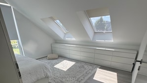 Een moderne zolderkamer met dakramen, een bed, een bank en een vloerkleed.