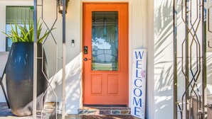 A house entrance with a red door, a welcome sign, and a large potted plant. - 4-bedroom, 2-bathroom house with pool, hot tub and PS-5 in Clearwater (Clearwater)
