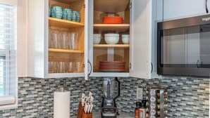 A kitchen with a built-in cabinet containing glassware, bowls, and plates. A blender and spice jars are on the counter. - 4-bedroom, 2-bathroom house with pool, hot tub and PS-5 in Clearwater (Clearwater)