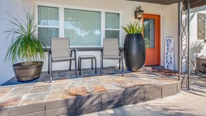A patio with a potted plant, two chairs, a large planter, and a welcome sign. - 4-bedroom, 2-bathroom house with pool, hot tub and PS-5 in Clearwater (Clearwater)
