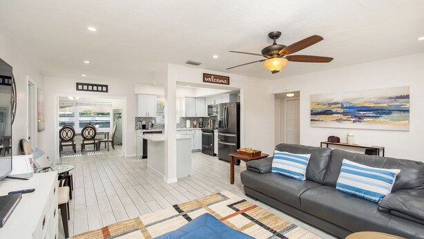 A modern living room with a grey sofa, a coffee table, and a ceiling fan. - 4-bedroom, 2-bathroom house with pool, hot tub and PS-5 in Clearwater (Clearwater)