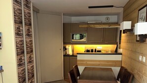 Ein kompakter Wohnraum mit Küchenzeile, Essbereich und einer Couch.