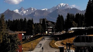 Blick auf einen Berg mit Seilbahn und einem roten Gebäude im Vordergrund.