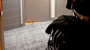 Ein Zimmer mit geschlossener Tür, einem gemusterten Teppich und einem Kinderwagen.