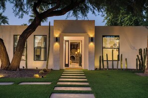 A modern building with a central entrance, surrounded by a well-maintained lawn and cacti. - Desert Haven: 4BR w/ Pool, Grill & Chef’s Kitchen (Scottsdale)