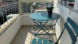 A balcony with a table and chairs, a potted plant, and a view of the cityscape. - Tirana Central Square View (Tiranë)