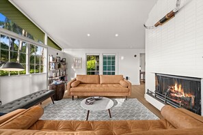 A modern living room with a fireplace, a sofa, a bench, and a bookshelf.