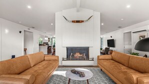 A modern living room with a fireplace, two leather sofas, a coffee table, and a patterned floor.