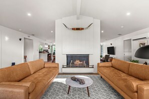 A modern living room with a fireplace, two leather sofas, a coffee table, and a patterned floor.