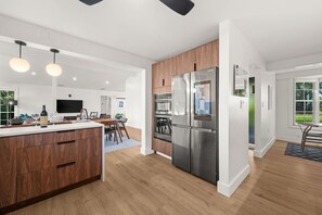 A modern kitchen with a stainless steel refrigerator, wooden cabinets, and a dining area with a table and chairs.