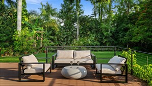 An outdoor seating area with a sofa and chairs, a round table, and a railing.