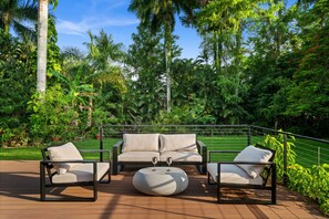 An outdoor seating area with a sofa and chairs, a round table, and a railing.