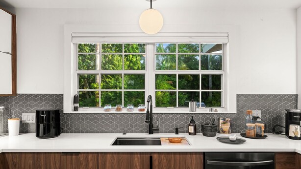 A modern kitchen with a large window, a coffee maker, a kettle, and a coffee machine. - Mid-Century Modern · River Walk · Historic McGregor (Fort Myers)