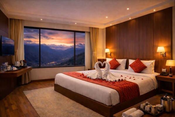 Une chambre d’hôtel avec un grand lit, une télévision, un bureau et une vue sur les montagnes.