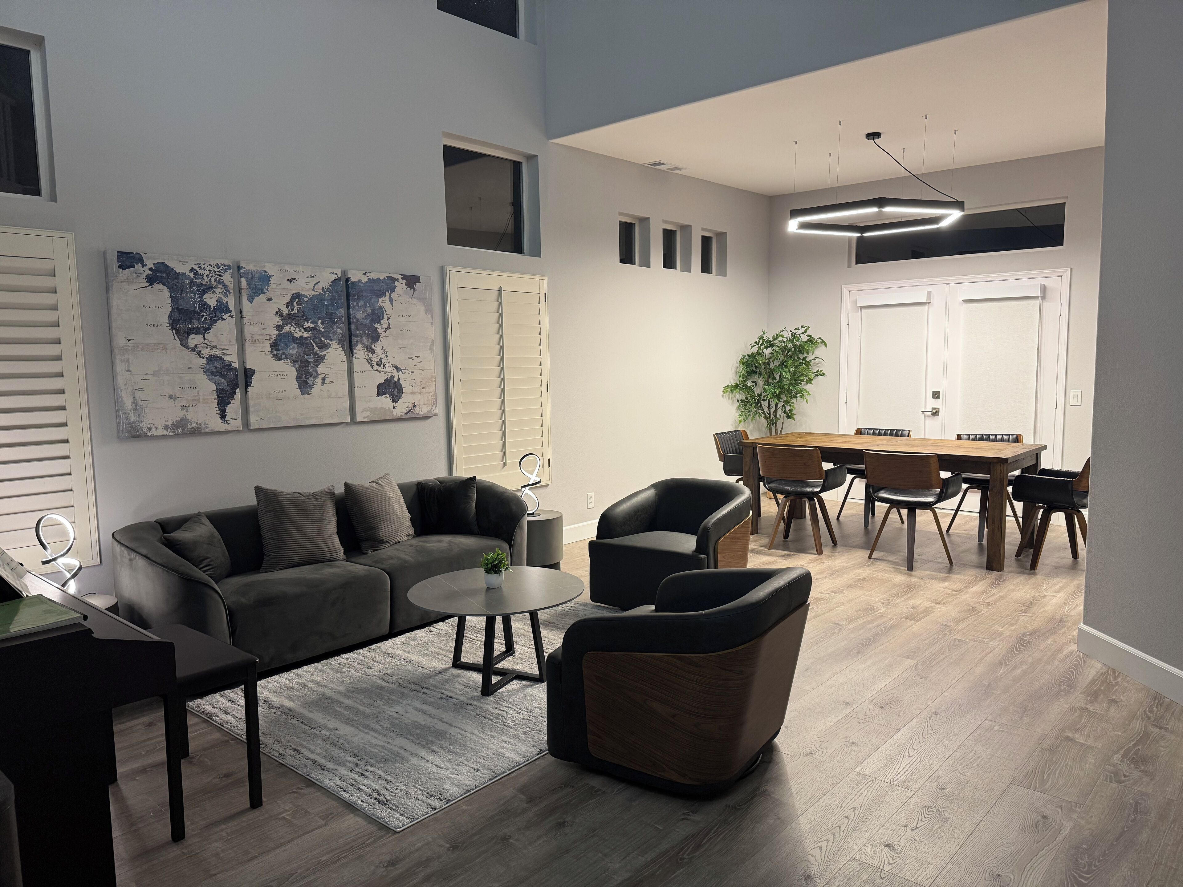 A modern living room with a grey sofa, a coffee table, and a dining area with a wooden table and chairs.
