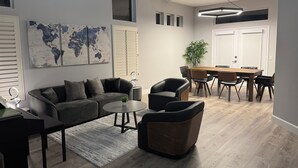 A modern living room with a grey sofa, a round coffee table, and a dining area with a wooden table and chairs. - Modern Remodeled Irvine Northwood Home (Irvine)