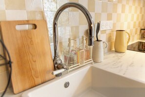 A kitchen sink with a faucet, a cutting board, and soap dispensers. - Maison Félicia - 2 air-conditioned suites with bathroom - Fontainebleau (Moret-Loing-et-Orvanne)