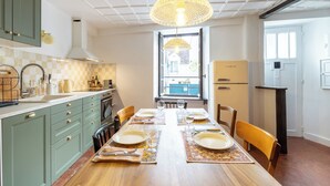 Une cuisine avec une table à manger pour quatre personnes, une fenêtre donnant sur un beau paysage et un réfrigérateur.