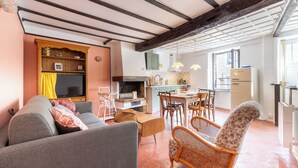 Un salon confortable avec un canapé, des fauteuils et un téléviseur. Il y a également un coin cuisine avec une table et des chaises.