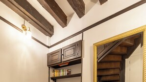 Un couloir doté d’un plancher en bois, d’une bibliothèque remplie de livres et d’un miroir avec un cadre doré.