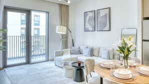 Een moderne woonkamer met een bank, eettafel en een balkon met uitzicht op gebouwen.
