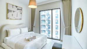 Een moderne hotelkamer met een groot bed, uitzicht op de stad en een groot raam met gordijnen.