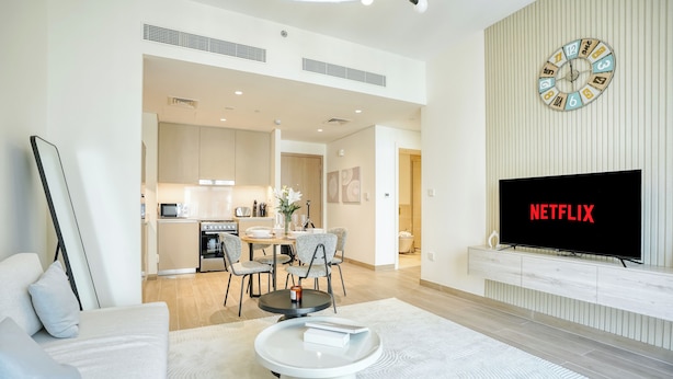 A modern living room with a sofa, coffee table, and a TV displaying "NETFLIX".