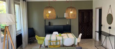 A modern living room with a sofa, dining table, chairs, and a TV.
