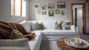 A living room with a white sofa, a brown blanket, and a tray of decorative items on a wooden coffee table.